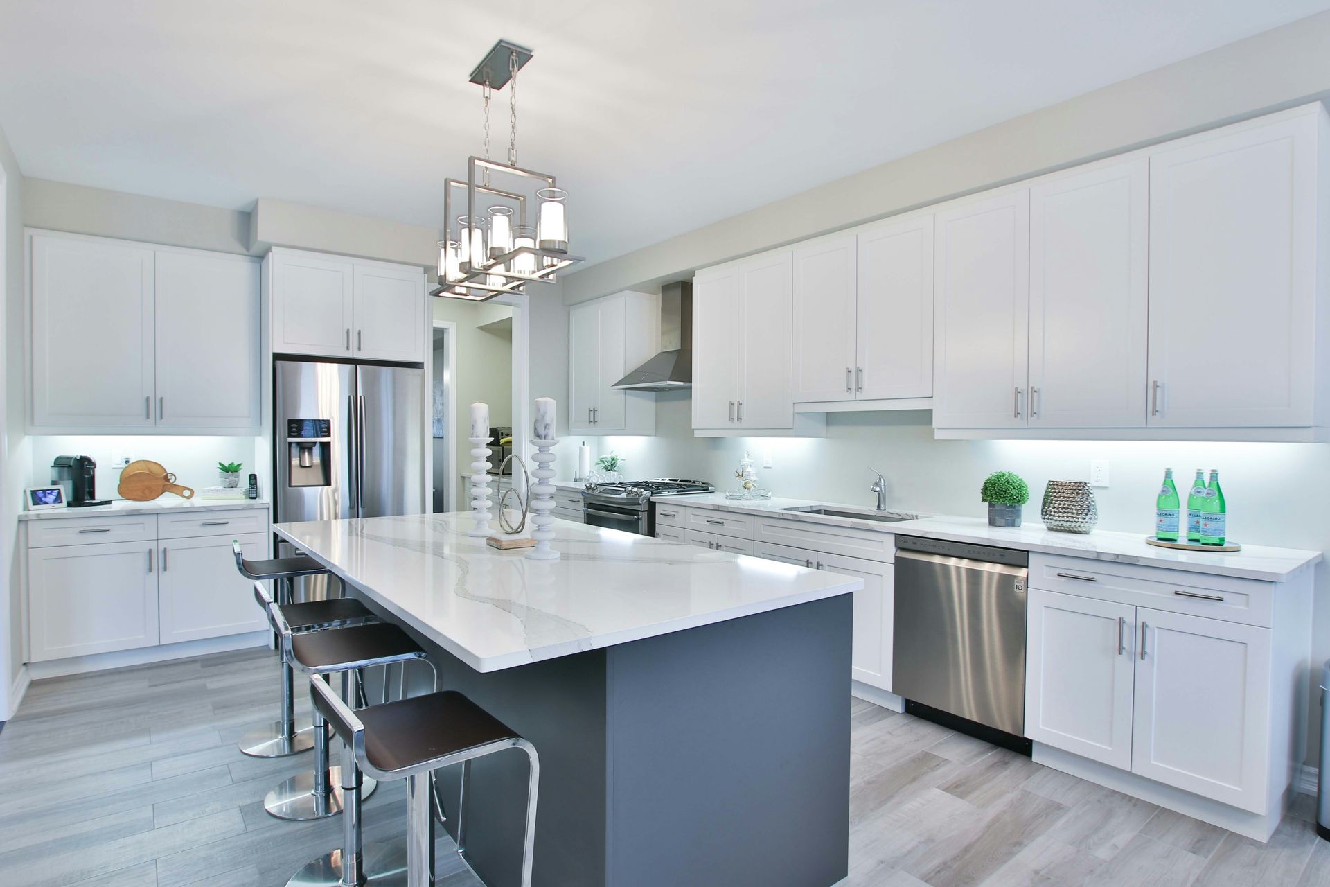 A modern kitchen with white cabinets, a dark island, and stainless steel appliances